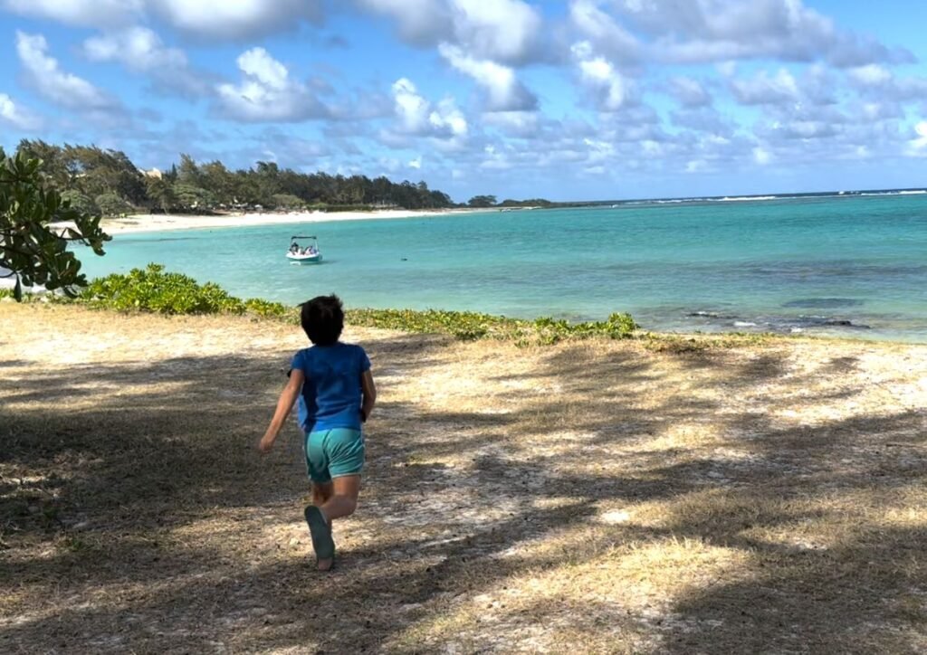 quand partir à l'ile maurice ? Mon fils qui se promène sur la plage de la Cambuse